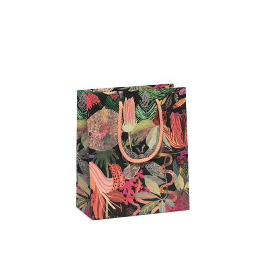 Multicolor floral print on black background with orange rope handles. Measuring 8"x4"x9.5", this Wild Kingdom Gift Bag is crafted from heavyweight coated paper, complete with a cotton rope handle and featuring charming illustrations by Michelle Morin.